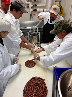 Students form sausage at the Meat Cutting School